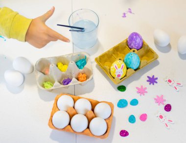 Paskalya yumurtalarını renkli boya ve süslemelerle boyarken, Paskalya kutlaması için hazırlanırken görülüyor.