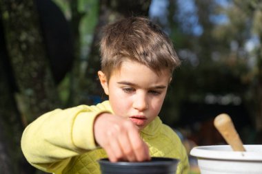 Genç bir çocuk açık havaya ot ekiyor, çocuklar için bahar baharı bahçe işleri yapıyor.