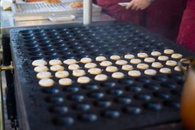 Delicious poffertjes cooking on a griddle at a street food stall, a popular dutch treat clipart