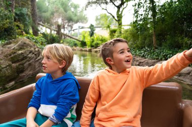 Resimli bir lunaparkta rahatça tekne gezintisi yapan iki genç çocuk.