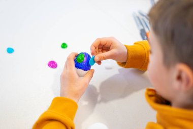 Paskalya yumurtalarını renkli çıkartmalar ve parıltılarla süsleyen çocuk yaratıcı bahar etkinliklerinin tadını çıkarıyor.