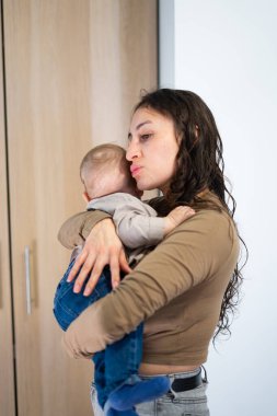 Anne, bebeğini şefkatle ve sevgiyle kucaklıyor. Yürek ısıtan bir annelik sevgisiyle.