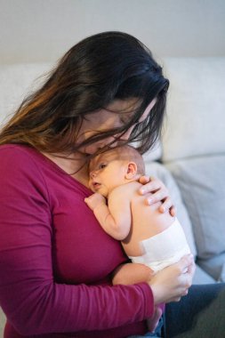 Anne yeni doğmuş bebeğini şefkat ve şefkatle kucaklıyor. Yürek ısıtan bir bağ anı yaratıyor.