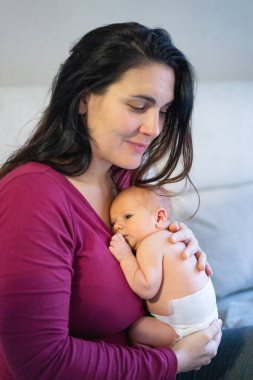 Anne, yeni doğmuş bebeğini nazikçe göğsüne yakın tutuyor. Yürek ısıtan bir bağ kuruyor.