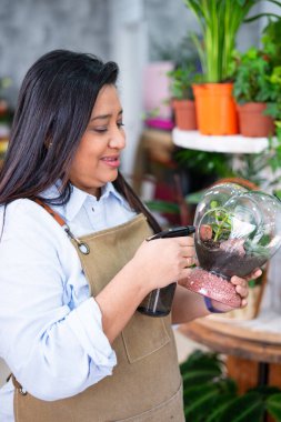 Çiçekçide cam akvaryumun içindeki çiçeklerle ilgilenen bir çiçekçi.