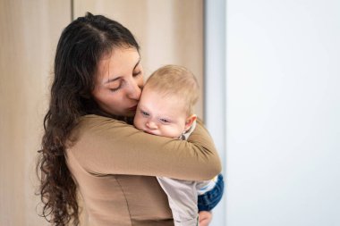 Anne sevgiyle bebeğini kucağında tutuyor.
