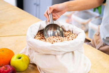 Sıfır atık bakkalından fasulye toplayan bir dükkan sahibinin yakın plan fotoğrafı. Sürdürülebilir alışverişi teşvik ediyor.