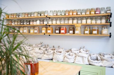 Çeşitli gıda ürünleriyle dolu cam kavanozlar ve kumaş torbaları, sürdürülebilir alışveriş uygulamalarını desteklemek için sıfır atık mağazasındaki raflarda düzenli olarak düzenleniyor.