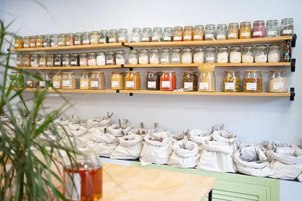 Çeşitli gıda ürünleriyle dolu cam kavanozlar ve kumaş torbaları, sürdürülebilir alışveriş uygulamalarını desteklemek için sıfır atık mağazasındaki raflarda düzenli olarak düzenleniyor.