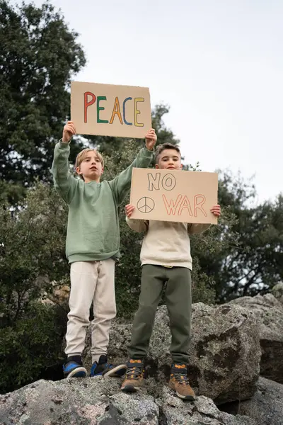 İki genç eylemci ellerinde barış ve savaş mesajı olmadan protesto işaretleri tutuyorlar.