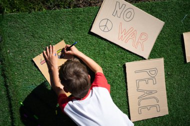 Barış gösterisine hazırlanan barış sembolleri çizen çocuk