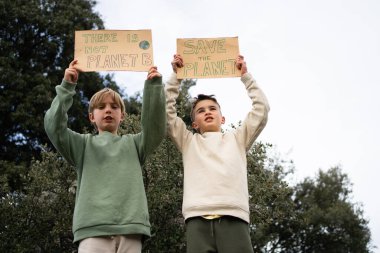 İki genç eylemci, gezegeni kurtarmakla ilgili protesto işaretleri tutuyorlar.