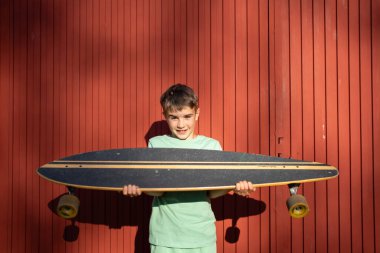 Renkli arka planlara karşı gururla uzun pano sergileyen çocuk, açık hava aktivitelerinin keyfini çıkarıyor.