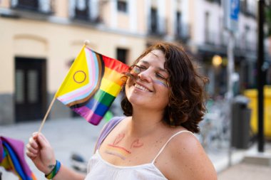 Igbtq + topluluğunu kutlama töreninin keyfini çıkarırken cinsiyetler arası gelişim gösteren gurur bayrağı sallayan mutlu kadın.