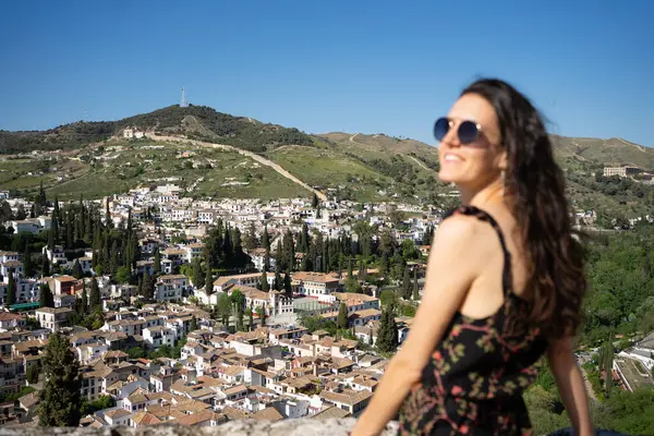 Geleneksel beyaz evleri ve yemyeşil bitkileriyle İspanya 'nın Granada şehrinin manzarasına hayran olan bir turist.