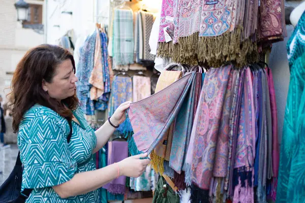 Turist, sokak pazarında renkli bir paşmina seçiyor.