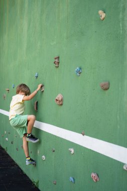 Çocuk tırmanma antrenmanı duvarı açık alanda eğleniyor.
