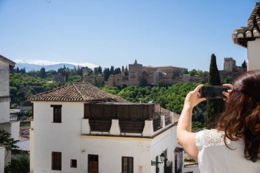 Granada 'daki Alhambra Sarayı' nın fotoğrafını çeken bir turist, Sierra Nevada Dağları ile İspanya