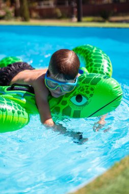 Çocuk yaz tatilinin tadını çıkarıyor. Arka bahçede şişme oyuncakla oynuyor.