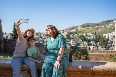 Turistler arka planda Albaisin Mahallesi, Granada, Endülüs ve İspanya 'da akıllı telefonlarıyla selfie çekiyorlar.