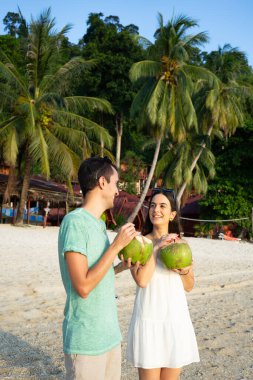 Tayland 'da güzel bir sahilde hindistan cevizinden içen turistler tatillerinin tadını çıkarıyorlar.