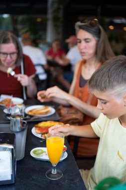 Aile bir kafede tost, portakal suyu ve diğer yiyeceklerle kahvaltı yapıyor.