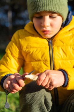 Delikanlı çakı kullanarak odun kesiyor, kış öğleden sonranın tadını çıkarıyor.