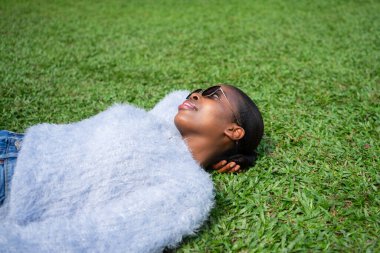 Serene genç kadın canlı yeşil çimenlerde uzanıyor, huzur ve sükunetin tadını çıkarıyor.