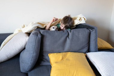 Çocuk ve köpeği kanepenin altından gözetliyor, evde birlikte oyun oynuyorlar.