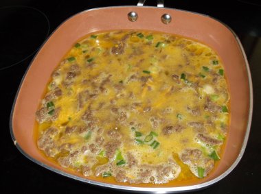 Sığır eti, peynir ve yeşil soğanlı yumurta omleti, zeytinyağında sotelenmiş. Pişir, katla ve servis yap..