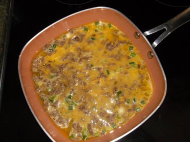 Sığır eti, peynir ve yeşil soğanlı yumurta omleti, zeytinyağında sotelenmiş. Pişir, katla ve servis yap..