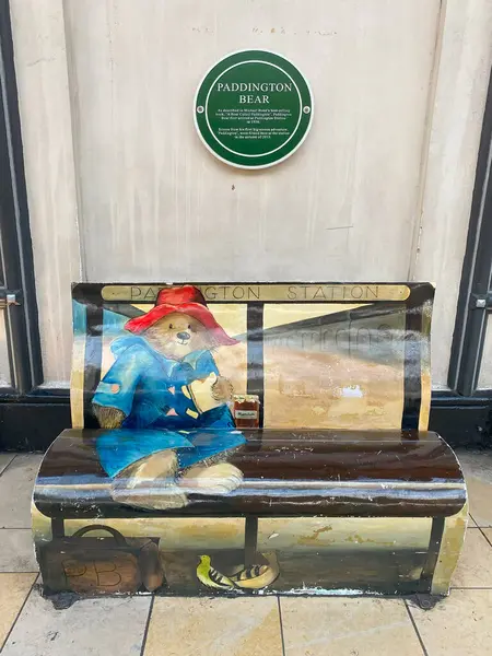 Paddington İstasyonu 'ndaki halka açık bir bankta Paddington Ayısı' nın renkli bir duvar resminin tam kare görüntüsü. Ayı klasik şapkası ve spor ceketiyle bir kavanoz marmelatla otururken tasvir edilir.. 