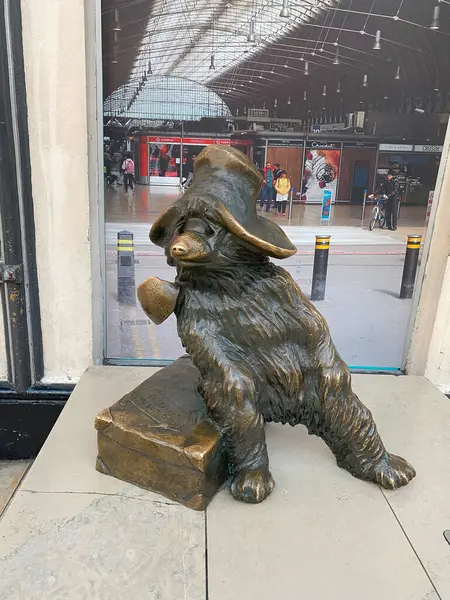 Paddington Ayısı 'nın Londra' daki Paddington İstasyonu 'ndaki bronz heykelinin düşük açılı çekimi. İkonik şapkasını takan ve üzerinde 