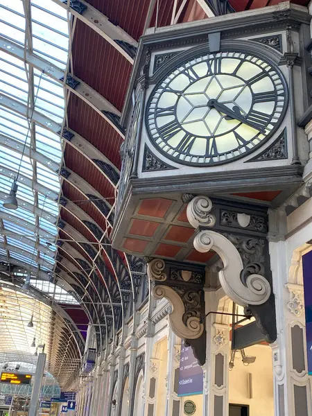 Ünlü Viktorya dönemi saatini ve Londra 'daki Paddington İstasyonu' nun geniş, kemerli cam çatısını gösteren yüksek açılı bir çekim. Fotoğraf istasyonun etkileyici mühendislik ve mimari güzelliğini vurguluyor.