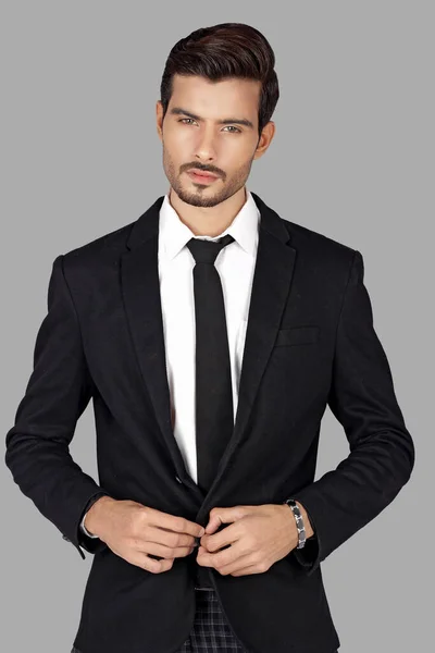 stock image young man in black suit and tie posing on grey background