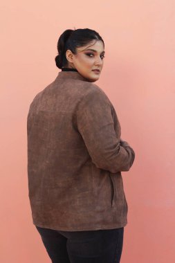 Pembe bir duvarın önünde duran bir kadın