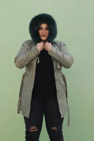 Uzun yeşil ceketli, siyah pantolonlu, kürk şapkalı bir kadın.