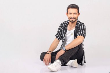 Genç yakışıklı adamın fotoğrafı. Yerde otur. Ekose gömlek giy.