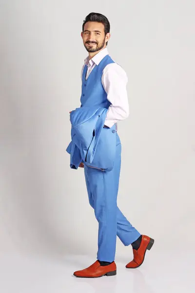 Hafif arka planda poz veren takım elbiseli bir genç.