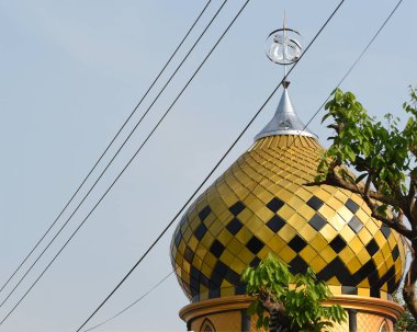 Altın sarısı, siyah kiremitleri ve Allah 'ın renklendirilmiş sembolü olan güzel bir cami.