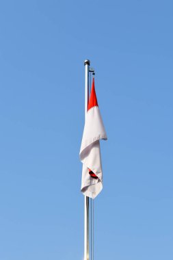 Bayrak direğindeki kırmızı beyaz Endonezya bayrağı açık mavi gökyüzü arka planına karşı