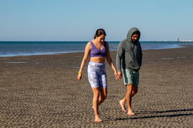 Sahilde yürüyen bir adam ve bir kadın. Meksikalı kardeşler yürüyor.