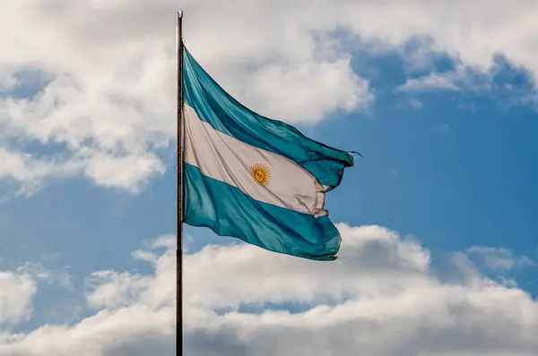 stock image Light blue and white Argentinian flag waving with blue sky and white clouds as background