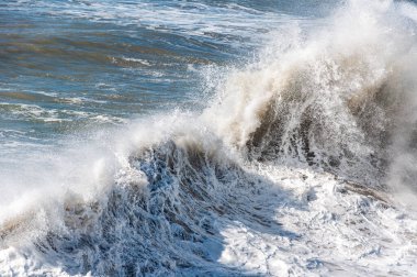 Deniz dalgaları kıyıdaki kayalara çarpıyor.