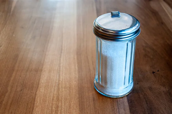 白糖玻璃瓶在木制桌子上装有白糖的玻璃瓶 — 图库照片