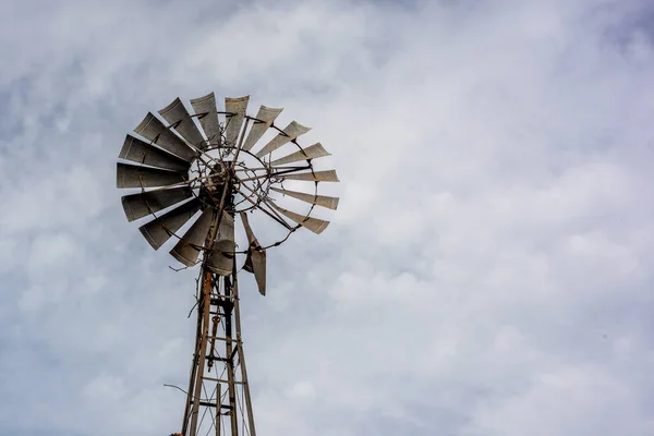 A broken windmill for water extraction with cloudy blue sky as background