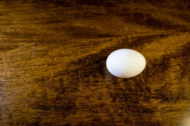 Tahta bir masada beyaz bir tavuk yumurtası.