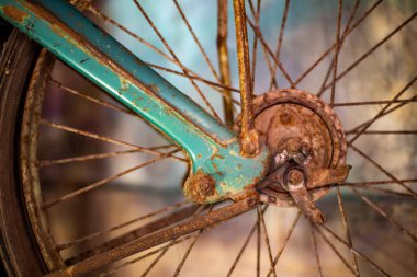 Eski bir motosikletin ön paslı tekerleği.