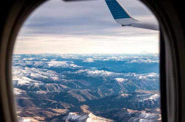 日の出に飛行機の窓からアンデス山脈を覆った雪の眺め — ストック写真