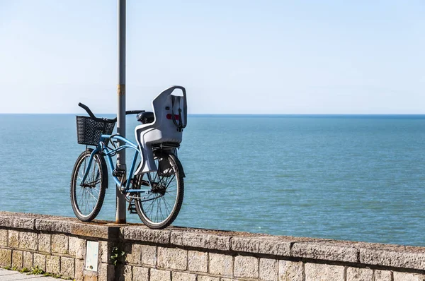 Stock image A bicycle tied to a column of light on the coast, with the blue sea as a background